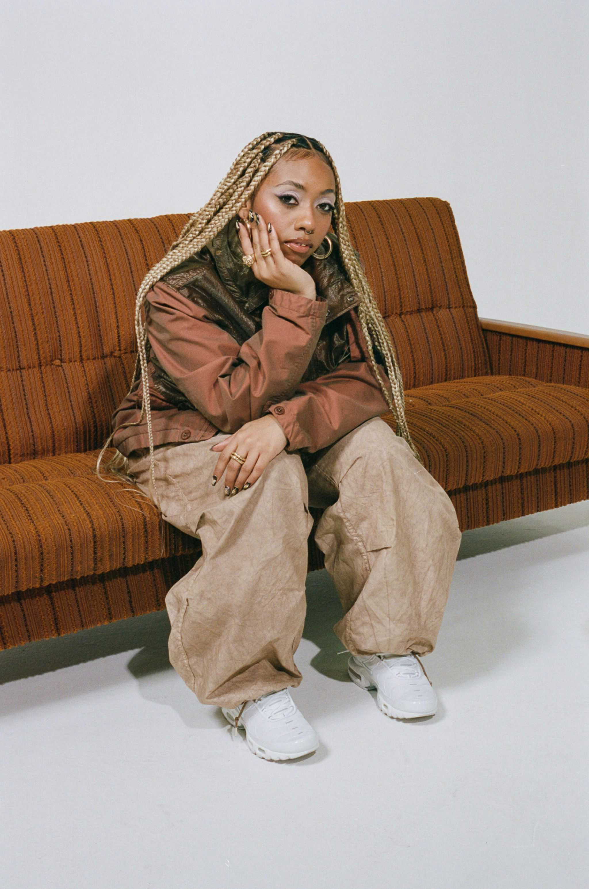 Bilde av artisten Nia Archives som sitter på en brun 70-tallssofa