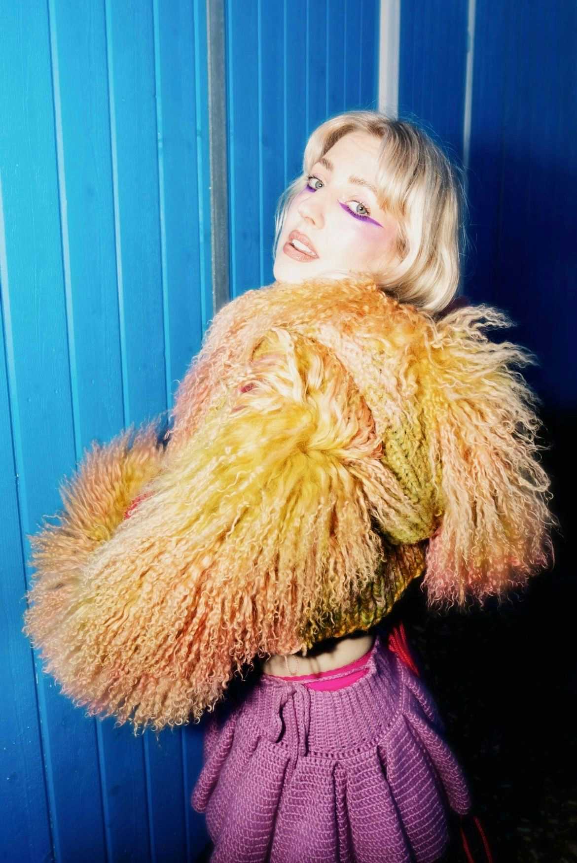Bilde av artisten Veronica Maggio i fluffy jakke mot blåmalt vegg
